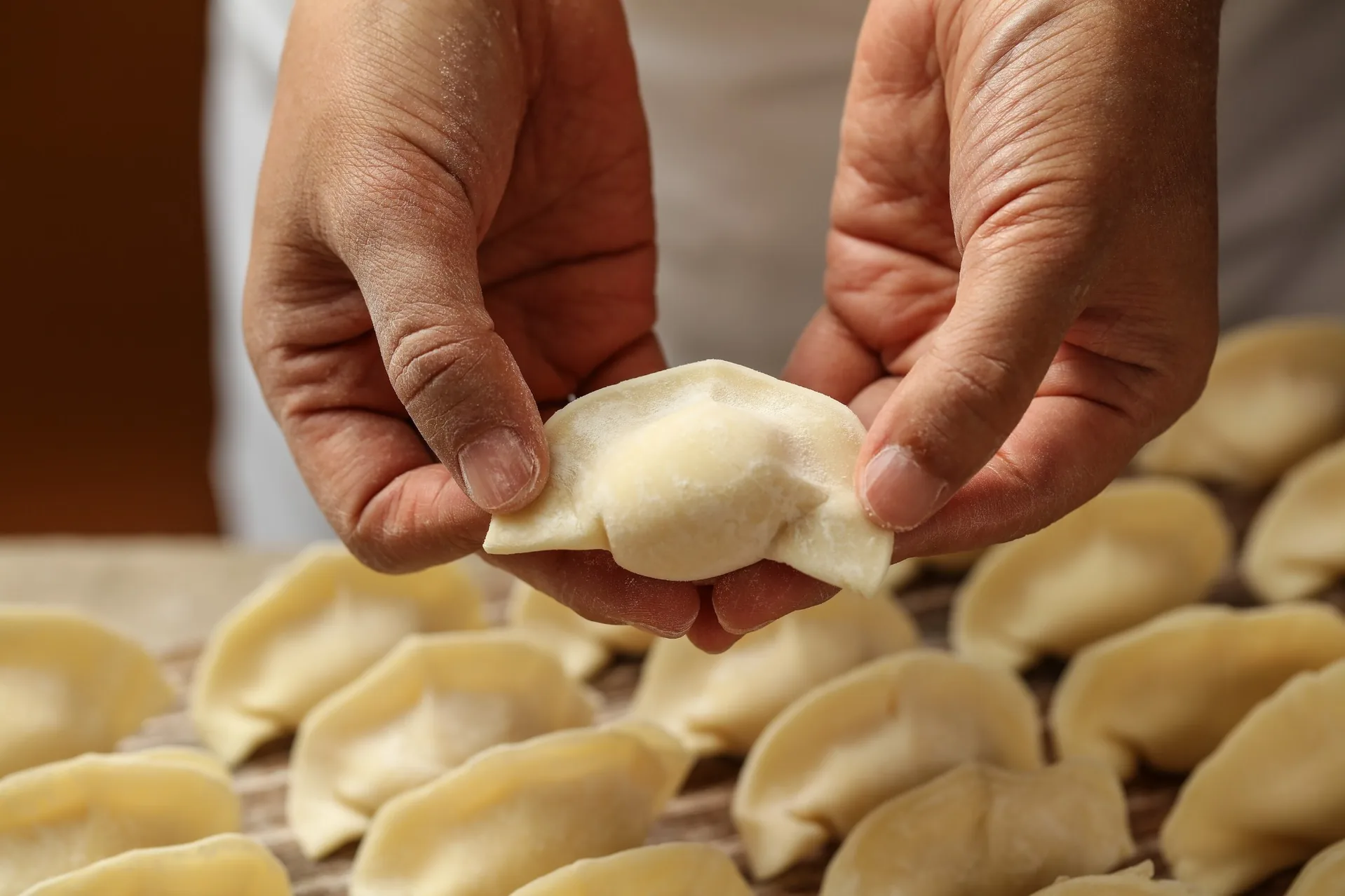 Two hands pinching a dumpling closed